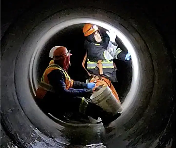Staff grouting a large pipe